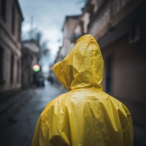 a person in a yellow raincoat walking down a street